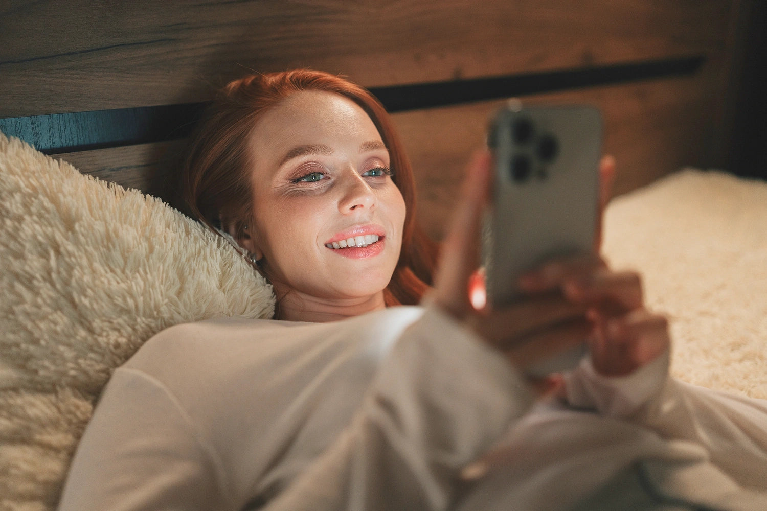 Frau die im Bett liegt und ihr Smartphone nutzt, biologische Uhr, gestoerter Schlaf